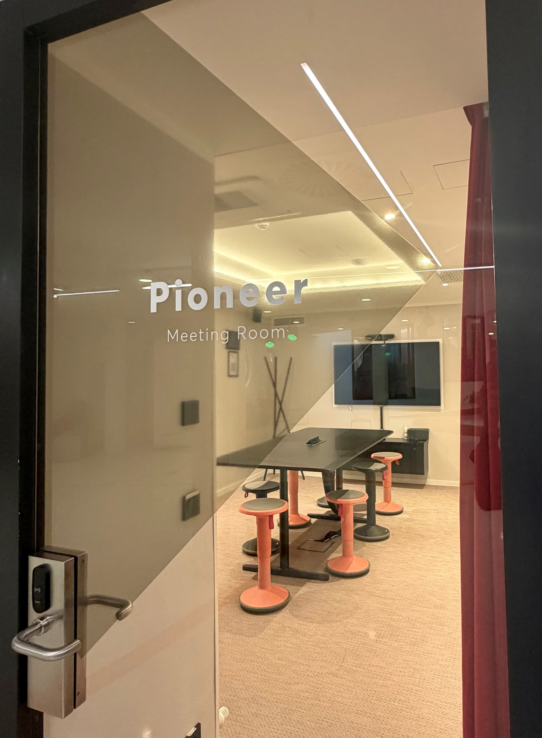 Vibrant 'Pioneer' meeting space with standing table at SPACE SHACK Coworking interior photo 2